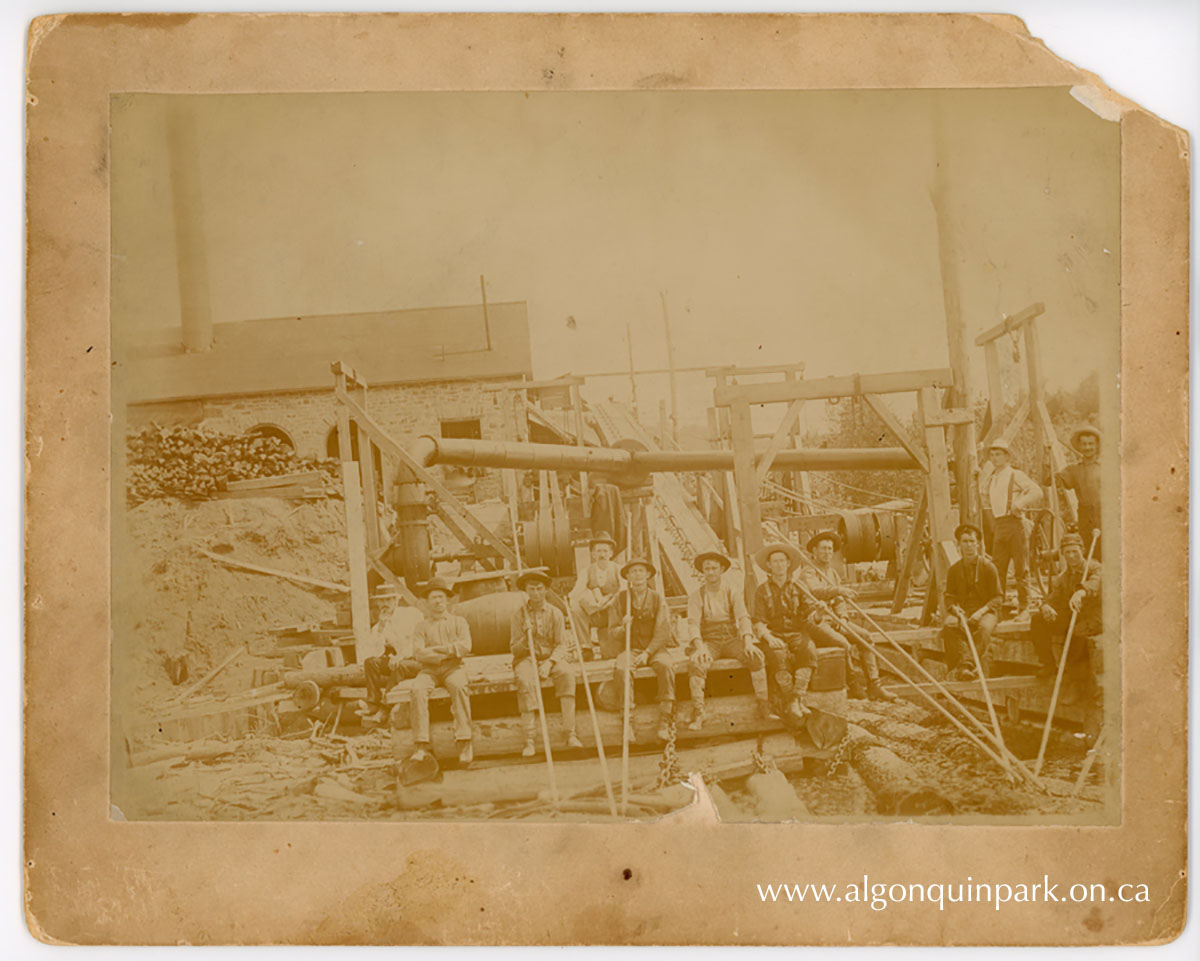 Men sit at the base of the first jackladder?with the powerhouse visible in the background, c. 1894 - 1896. APPAC, 2024.33.5, In memory of Patrick O'Neill and Michael Joseph O'Neill. 