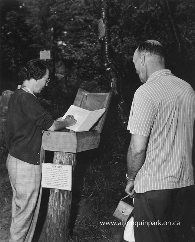 Image: Hikers signing a trail register book on a nature trail, 1953. Spot the signs in the trees. APPAC, APM 874. 