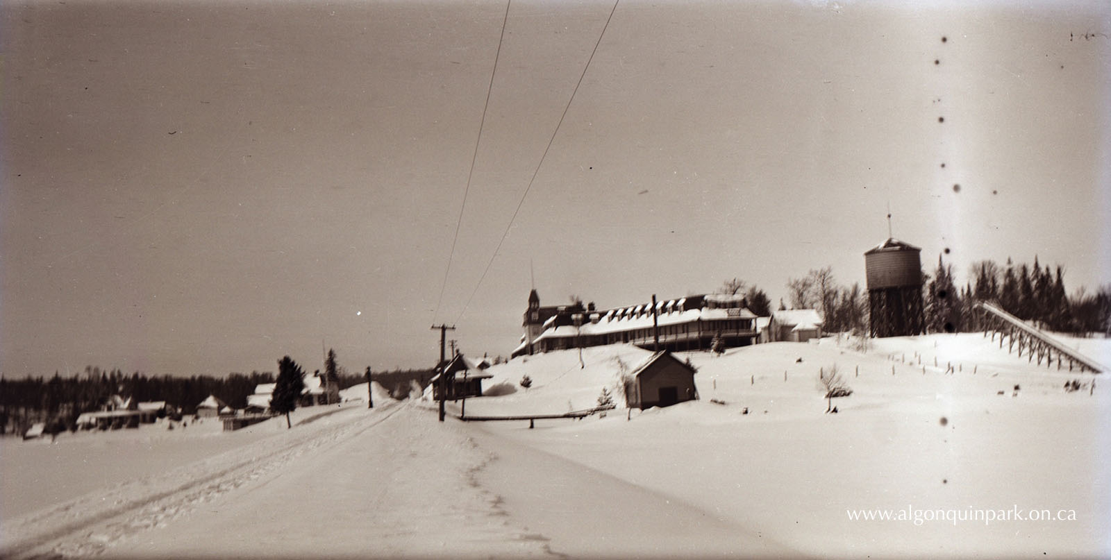 View of the Highland Inn, Winter 1915. The toboggan slide is visible on the far right. At the bottom of the hill below the hotel is Algonquin Park Station and the railroad tracks. APPAC, 1995.1.9, Collection of Harry and Adele Ebbs. 