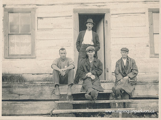 Ranger William Hughes standing behind three men, Brent, Cedar Lake, c. 1917-1920. The others are likely Rangers as well; note the badge on the shirt of the man on the left. APPAC, 2021.18.12. Estate of Janet Ivel (Hughes) Gurr.